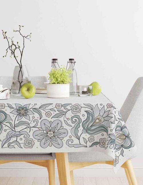 A tablecloth decorated with flowers and leaves, featuring green flowers, green apples, and flowers in a vase.